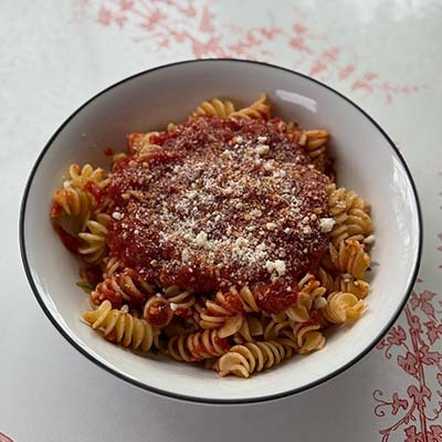 A comforting plate of pasta served with our slow simmered sauce and garnished with Parmesan Cheese.