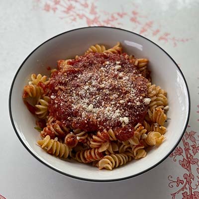 A comforting plate of pasta served with our slow simmered sauce and garnished with Parmesan Cheese.